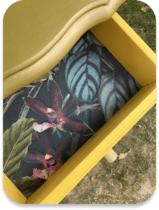 Tiroir d'une commode jaune dont le fond est tapissé d'un motif floral